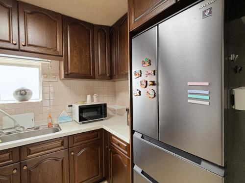 a kitchen with wooden cabinets and a stainless steel refrigerator at Direct to Shinjuku 15 mins 3rooms Up to 7 Guests in Tokyo