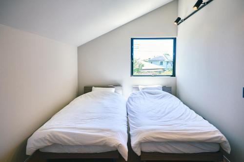 two beds in a room with a window at Neverland Garden A棟 - 山の中の別荘一棟貸切 in Ichigaya