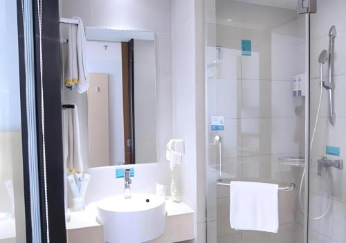a white bathroom with a sink and a shower at City Comfort Inn Nanning Shanglin Longhu Road in Shanglin