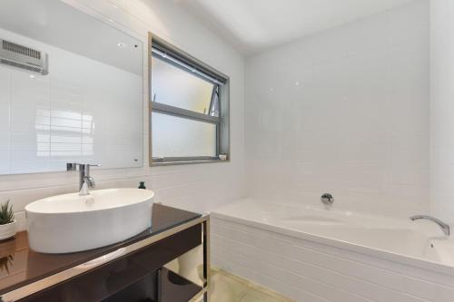 Baño blanco con lavabo y bañera en Waikawa Bay View - Waikawa Holiday Home, en Waikawa