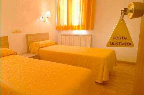 Habitación de hotel con 2 camas con sábanas amarillas en Hostal Muntanya, en Artesa de Segre