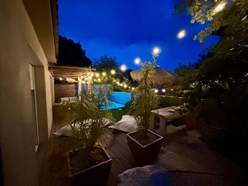 a patio with potted plants and a pool at night at Galibier Villa in La Celle-sous-Gouzon