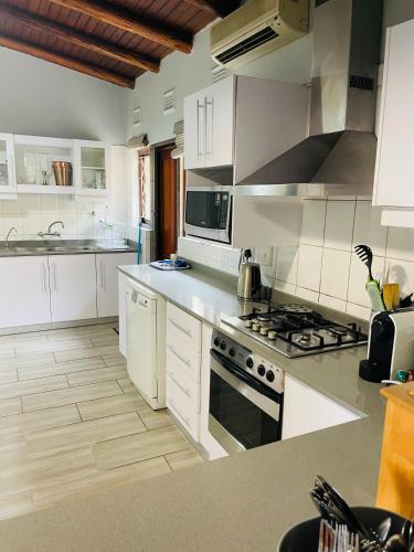 a kitchen with white cabinets and a stove top oven at 4 Bedroom Beach House on 4th Ave in Umdloti