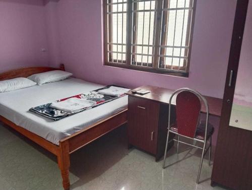 a bedroom with a bed with a desk and a chair at Hotel O Cozy Nest in Garacherāma
