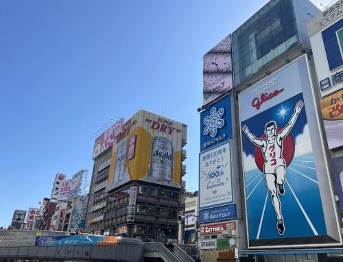 a city street with tall buildings and billboards at HOTEL AMANEK Osaka Namba in Osaka