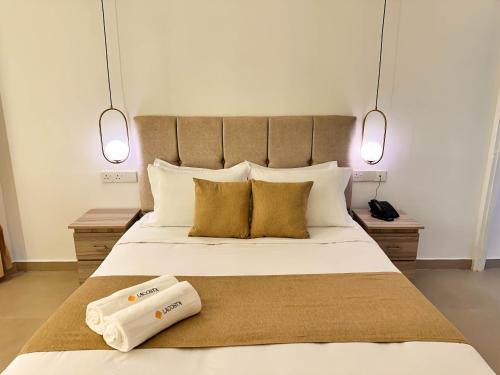 a bedroom with a large white bed with two lights at La Costa Hotel in Katunayake