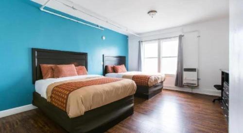 a bedroom with two beds and a blue wall at Stuart Hotel in Los Angeles