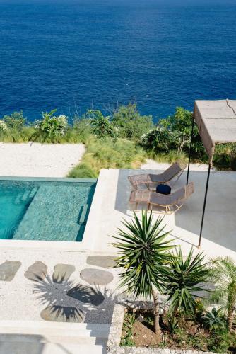 a swimming pool with two chairs and the ocean at Cliffside Haven in Nusa Penida in Nusa Penida