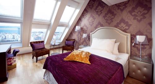 a bedroom with a bed and two chairs and windows at Clarion Collection Hotel Amanda in Haugesund