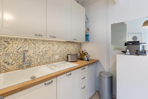 a kitchen with white cabinets and a sink at Arlequin by Cocoonr in Rennes