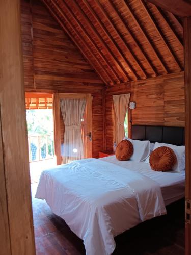 a bedroom with a large bed with white sheets at Pondok bluepo in Mendaya