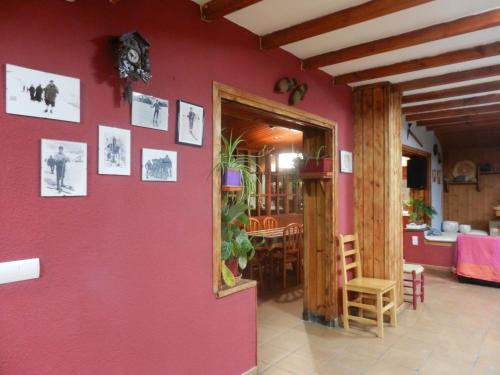 a room with a red wall with pictures on it at Albergue "El Aguila" in Candanchú