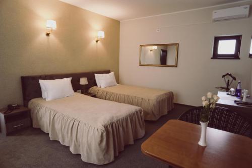 a hotel room with two beds and a table at C&C Residence Hotel in Bacău