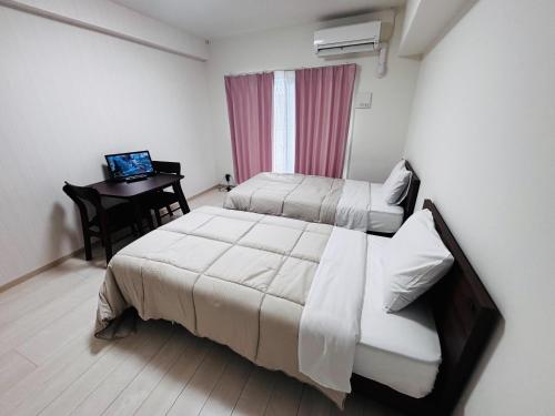 Un dormitorio con dos camas y un escritorio con una computadora portátil. en U&T V Five room505, en Beppu