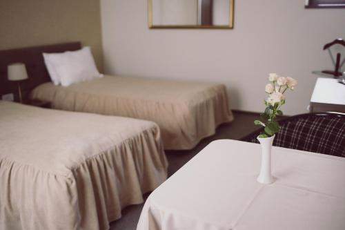 a hotel room with two beds and a vase with flowers on a table at C&C Residence Hotel in Bacău