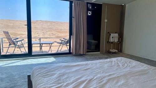 a bedroom with a bed and a view of the desert at Aurora desert camp in Bidiyah
