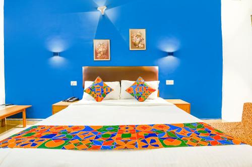 um quarto com uma cama com uma parede azul em FabHotel Benz Destination em Candolim