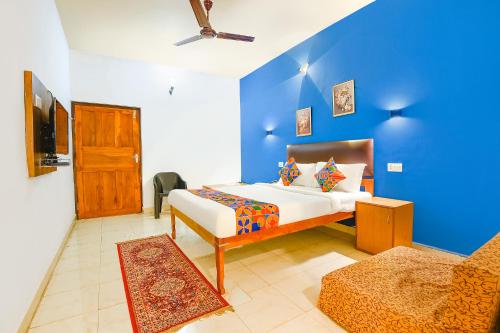 um quarto com uma cama e uma parede azul em FabHotel Benz Destination em Candolim