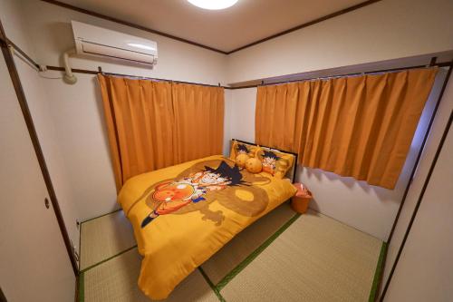 a small room with a bed with a yellow blanket at Kan'eiji-zaka Heim 寛永寺坂ハイム in Tokyo