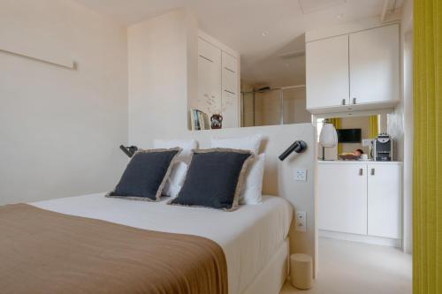 a white bedroom with a large bed with two pillows at MiHotel - La Maison Rose in Lyon