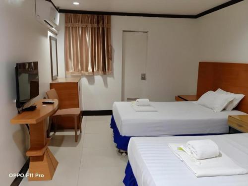 a hotel room with two beds and a desk and a television at Jeamco Royal Hotel - Pasig in Manila