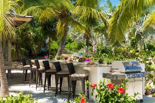a patio with a table and chairs and palm trees at The Oasis at Grace Bay in Grace Bay