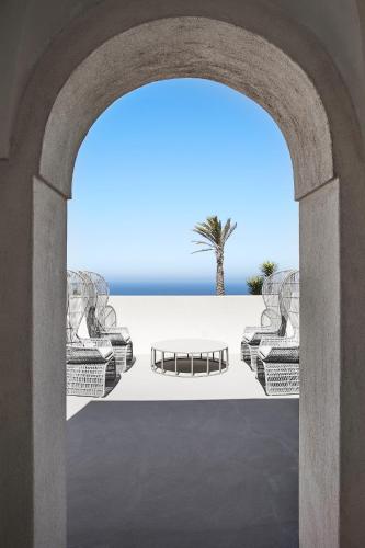 an archway with two chairs and a palm tree at Sikelia Luxury Hotel in Pantelleria