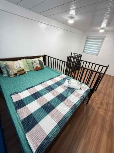 ein Schlafzimmer mit einem Bett mit einer karierten Decke in der Unterkunft Arzel's Tiny House in Mangatarem