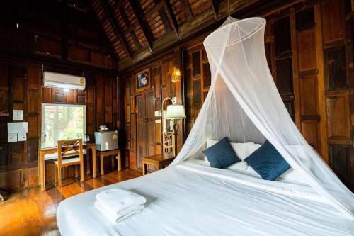 a bedroom with a bed with a mosquito net at Lamphurai Riverside in Ban Dong Klang