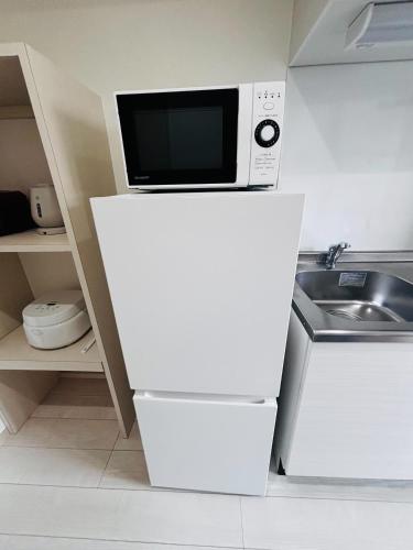 a microwave sitting on top of a white refrigerator at U&T V-Five Room-306 in Beppu