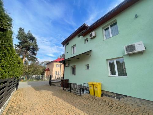 ein grünes Haus mit einer steinernen Einfahrt in der Unterkunft Casa Delia Vatra Dornei in Vatra Dornei