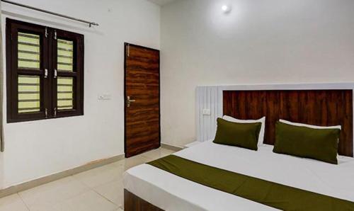 een slaapkamer met een groot wit bed met groene kussens bij FabHotel Rajhans in Gurgaon