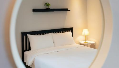 une chambre avec un lit blanc et un miroir dans l'établissement Sokcho pensionbyeol, à Sokcho