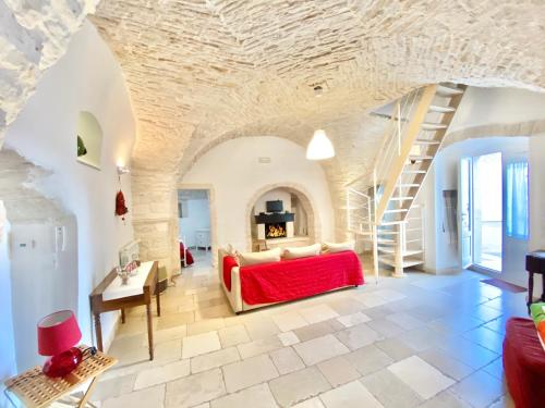 sala de estar con sofá rojo y escalera en Trullo Stella Luxury Trullo, en Alberobello