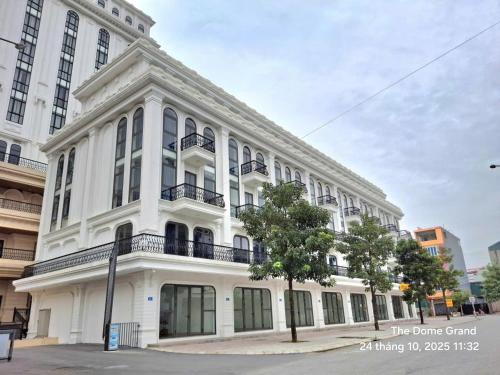 a white building with a tree in front of it at The Dome Grand in Ninh Lão