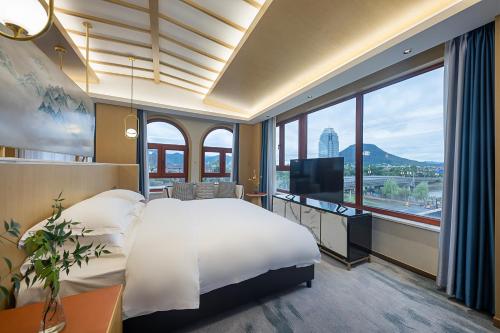 een hotelkamer met een bed en een groot raam bij Floral Luxury Hengdian Jiuqilu B&B in Longfengshan