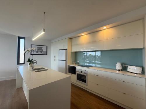 a kitchen with white cabinets and a counter top at Salty Stay Scarborough in Perth