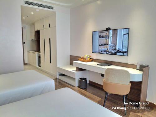 a bedroom with a desk with a tv and a bed at The Dome Grand in Ninh Lão