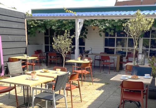 an outdoor seating area with tables and chairs and a pergola at Stylish Suite Steps To Shore in Zoutelande