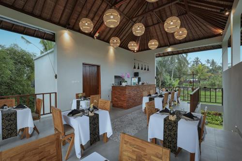 a dining room with white tables and chairs at Ascarya Ubud in Ubud