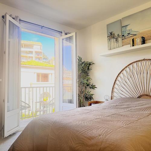 a bedroom with a bed and an open door to a balcony at Appartement Le Millie 3 chambres Hyper centre in Calvi