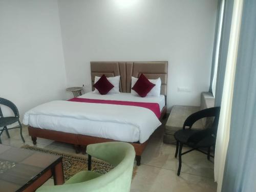 een slaapkamer met een bed met rode kussens en stoelen bij Hotel Kasauli Peak View - Family and Group Stay Apartments in Parwanoo