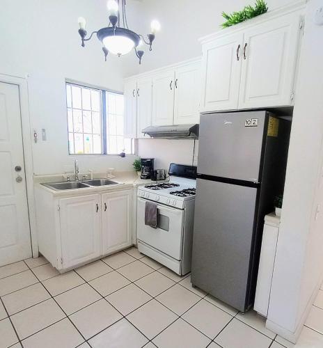 a white kitchen with a refrigerator and a sink at Casita Patz Ensenada in Ensenada