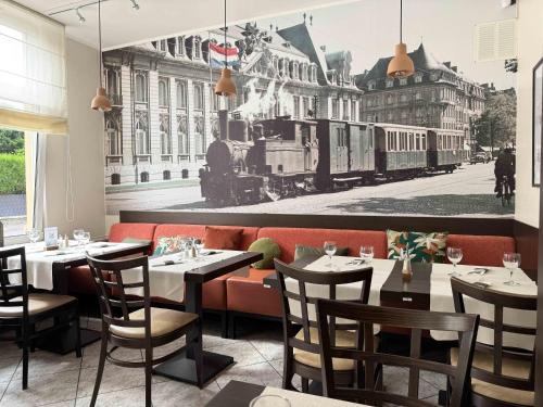 a restaurant with tables and chairs and a train mural at Charly's Gare in Senningerberg
