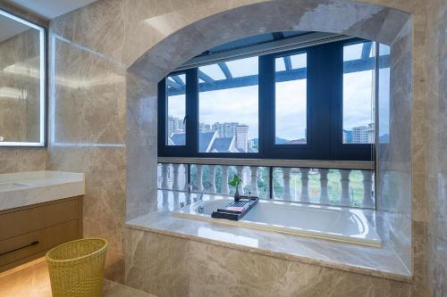 een badkamer met een bad en een raam bij Floral Luxury Hengdian Jiuqilu B&B in Longfengshan
