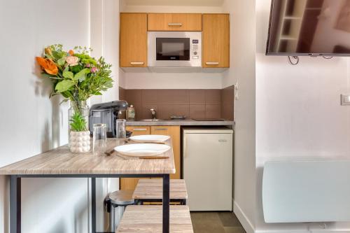 a kitchen with a table with a vase of flowers at Dalikyda L'escale Havraise Free Parking in Le Havre