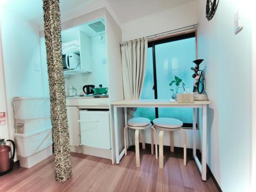 a small kitchen with a table and two stools at Moon Hotel in Tokyo
