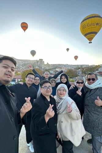 a group of people posing for a picture with hot air balloons at Zultanite Cappadocia Hotel in Nevşehir