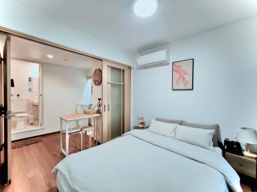 a white bedroom with a bed and a table at Moon Hotel in Tokyo