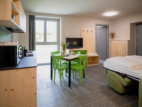 a room with a kitchen and a table with green chairs at Il nido di Siro in Cercino